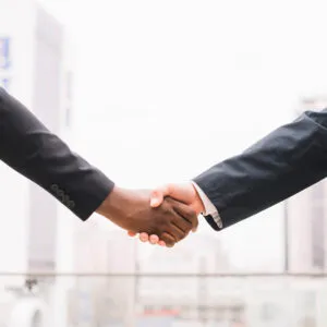 Two people in business suits shaking hands.